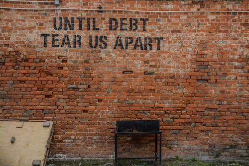 brick wall with the phrase "until debt tear us apart"